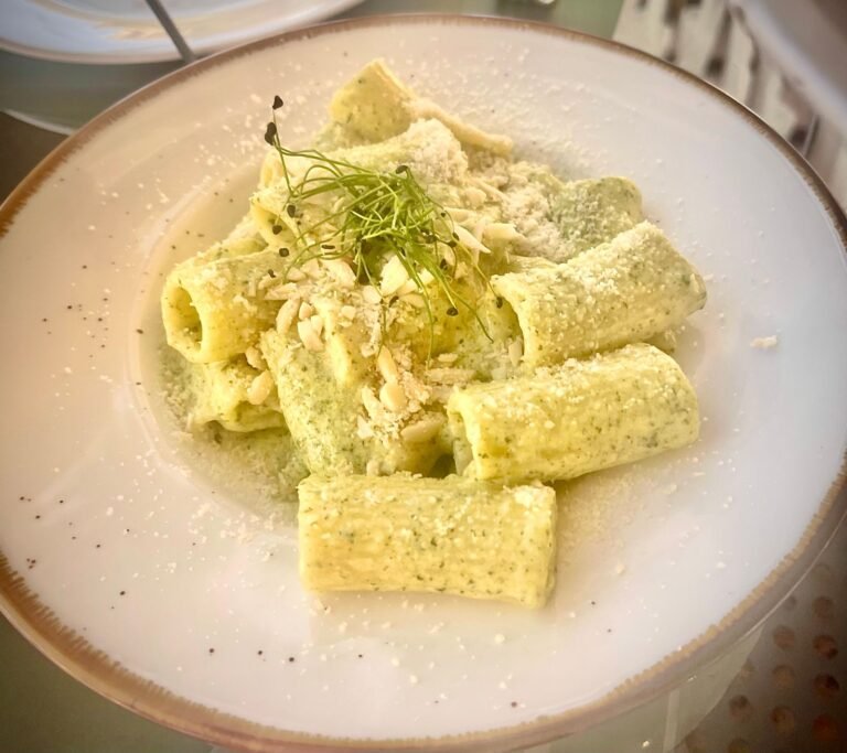 Creamy pesto rigatoni with melted cheese and fresh herb garnish