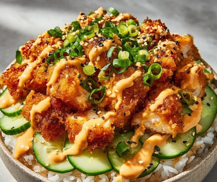 Crispy bang bang chicken bites with sweet-chili drizzle and green onions over rice