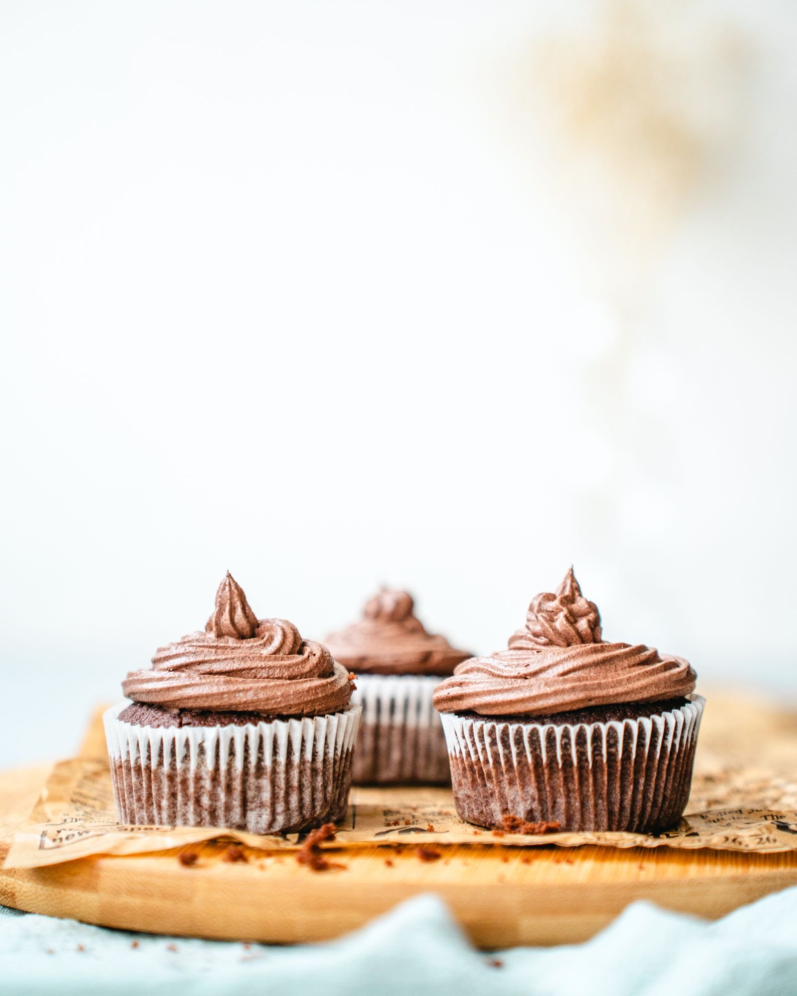 Black Velvet Cupcakes (Dark Cocoa, Black Buttercream, Ready in 1 Hour 10 Minutes) 3 Three chocolate cupcakes with piped chocolate frosting on a wooden board