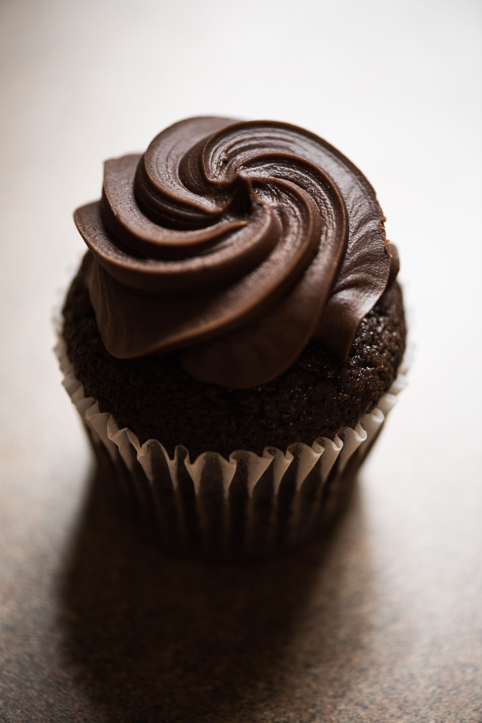 Black Velvet Cupcakes (Dark Cocoa, Black Buttercream, Ready in 1 Hour 10 Minutes) 2 A close-up of a very dark chocolate cupcake in a white paper liner with a tall swirl of dark chocolate buttercream frosting