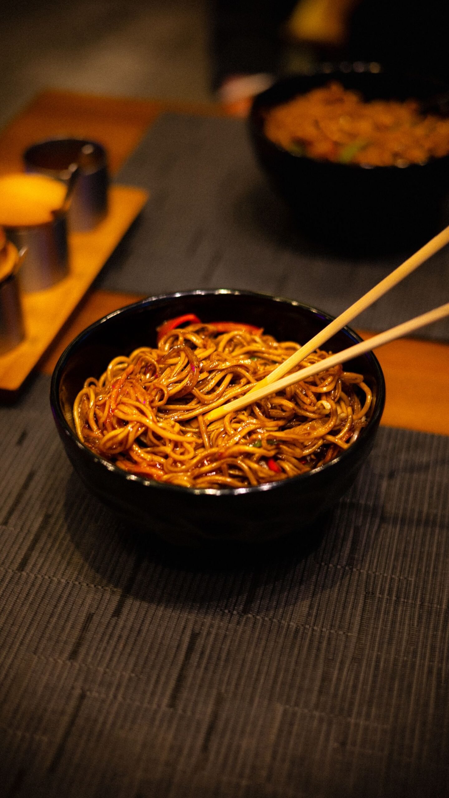 Chili Crunch Noodles (Spicy, Garlicky, Ready in 20 Minutes) 2 Black bowl of glossy chili crunch noodles with red chili pieces, chopsticks resting on the rim