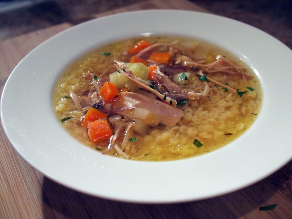 Classic Chicken Noodle Soup (Golden, Hearty, From-Scratch Comfort) 2 A white bowl of classic chicken noodle soup with shredded chicken, carrots, celery and small pasta in golden broth