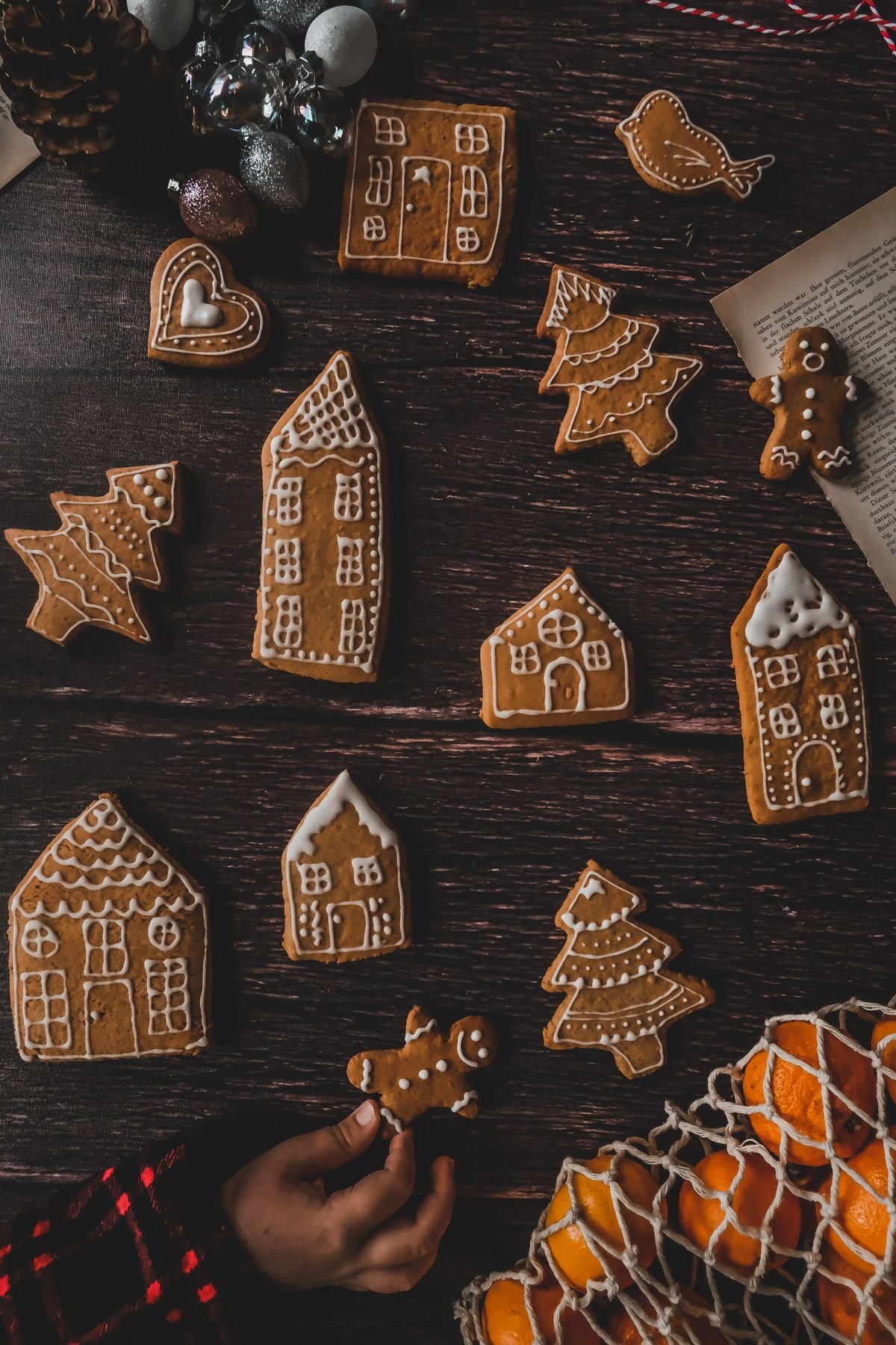Gingerbread houses, trees and gingerbread men with white icing on dark wood.