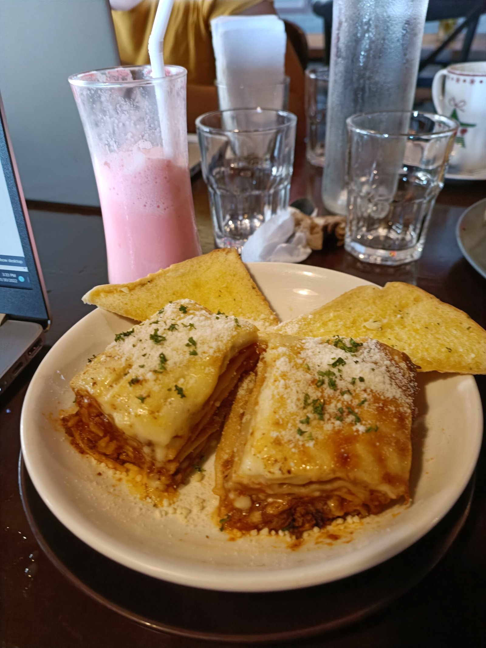 Two slices of classic lasagna with garlic bread