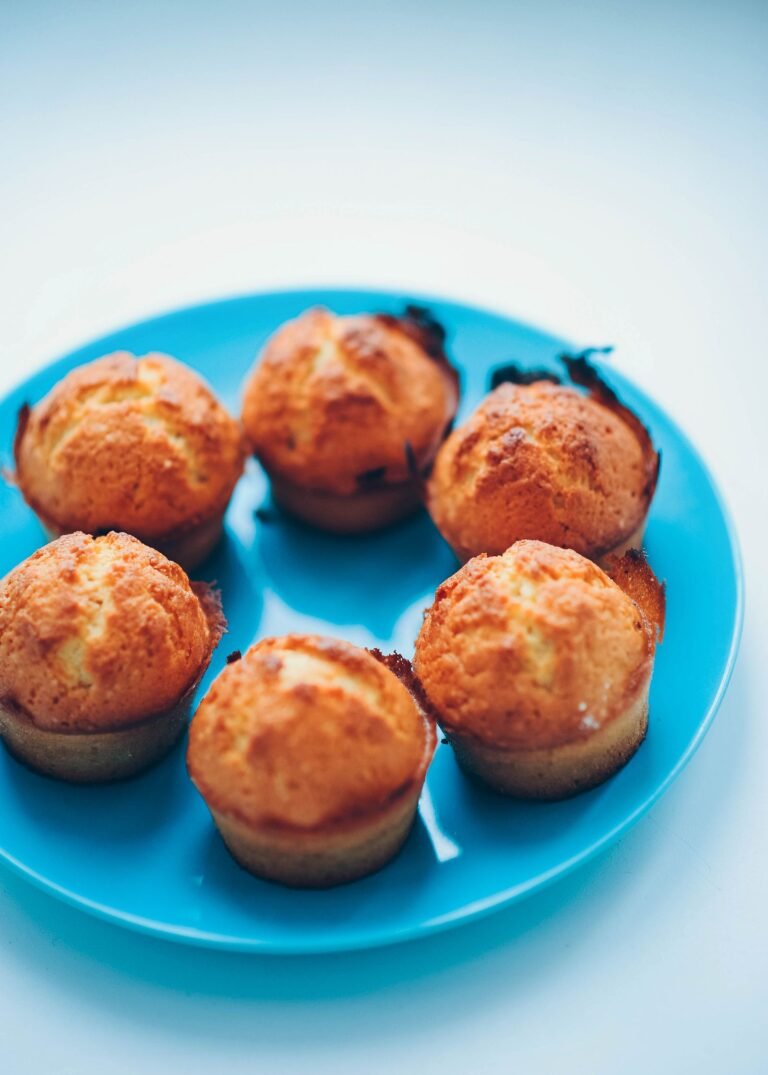 Six golden cottage cheese protein muffins on a bright blue plate