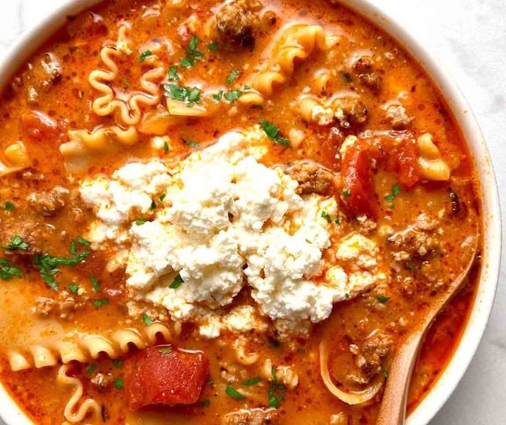 Top-down bowl of easy lasagna soup with ricotta, broken lasagna noodles and basil