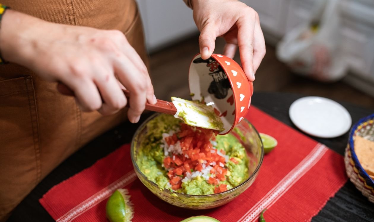 Piping the sour-cream spiderweb on guacamole