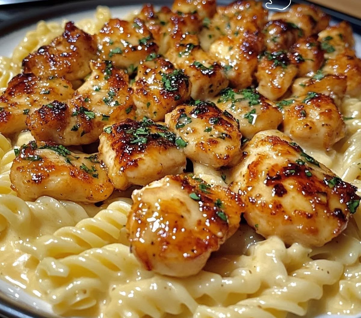 Honey butter garlic chicken bites glazed and served over creamy pasta