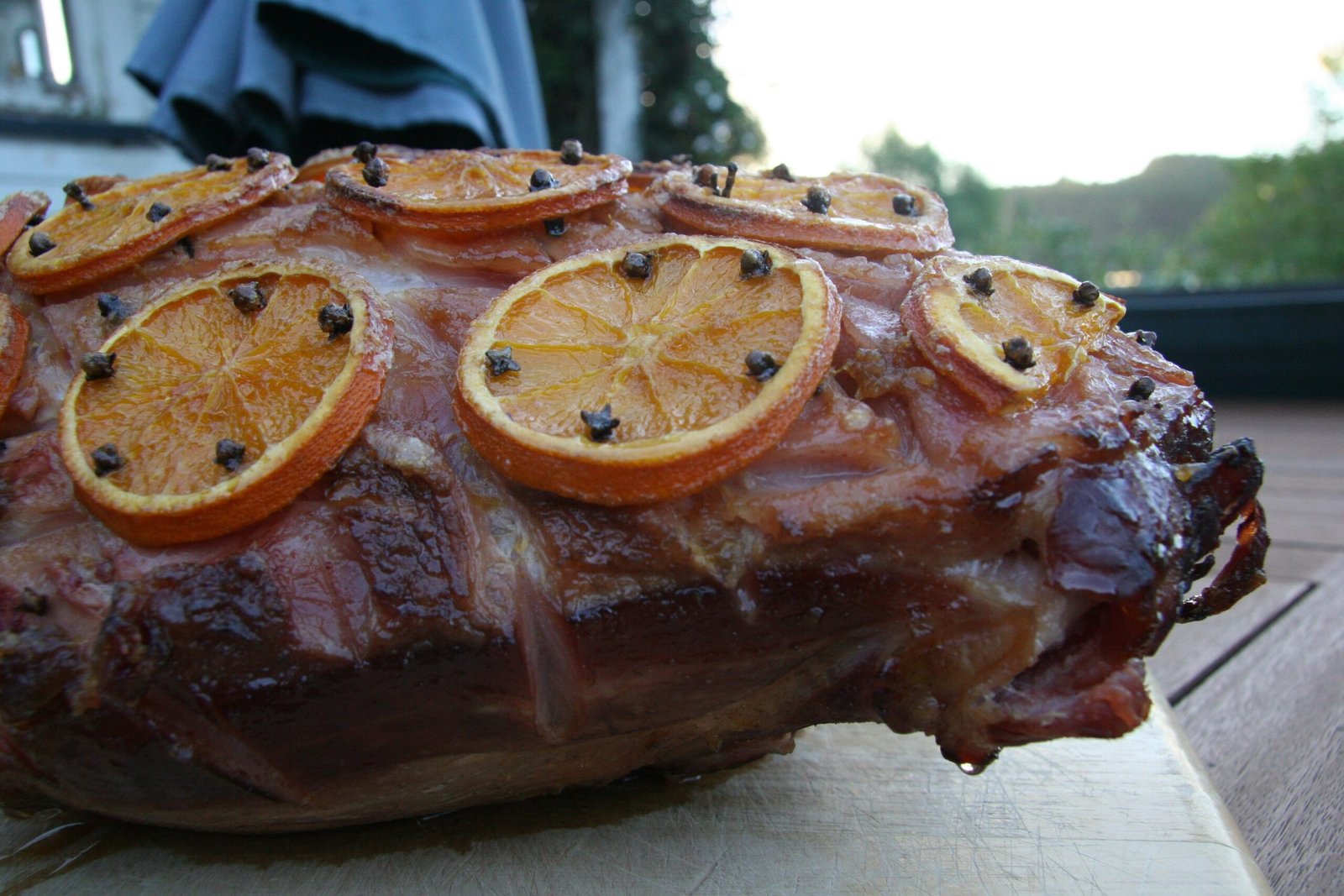 Glazed Christmas ham on a wooden board, studded with orange slices and whole cloves