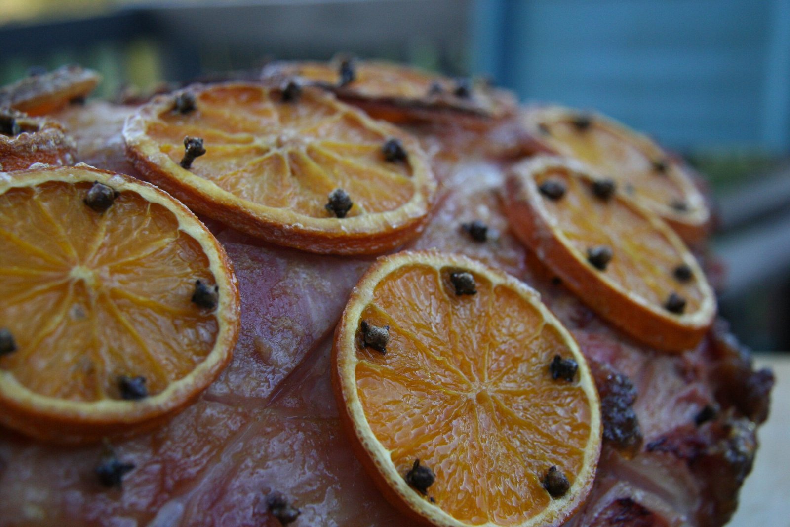 Close-up of a glossy honey-glazed Christmas ham topped with orange slices and whole cloves
