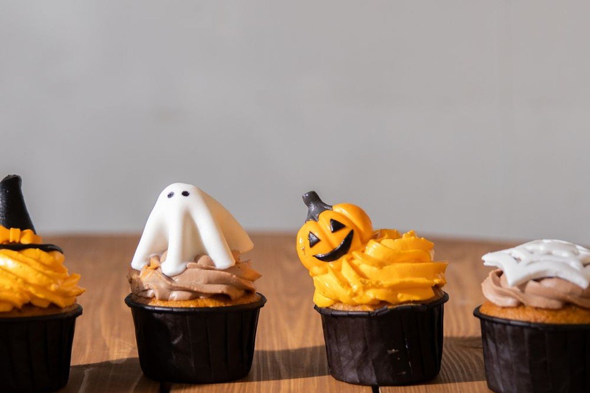 Row of mini Halloween cupcakes — ghost, jack-o'-lantern and witch hat designs