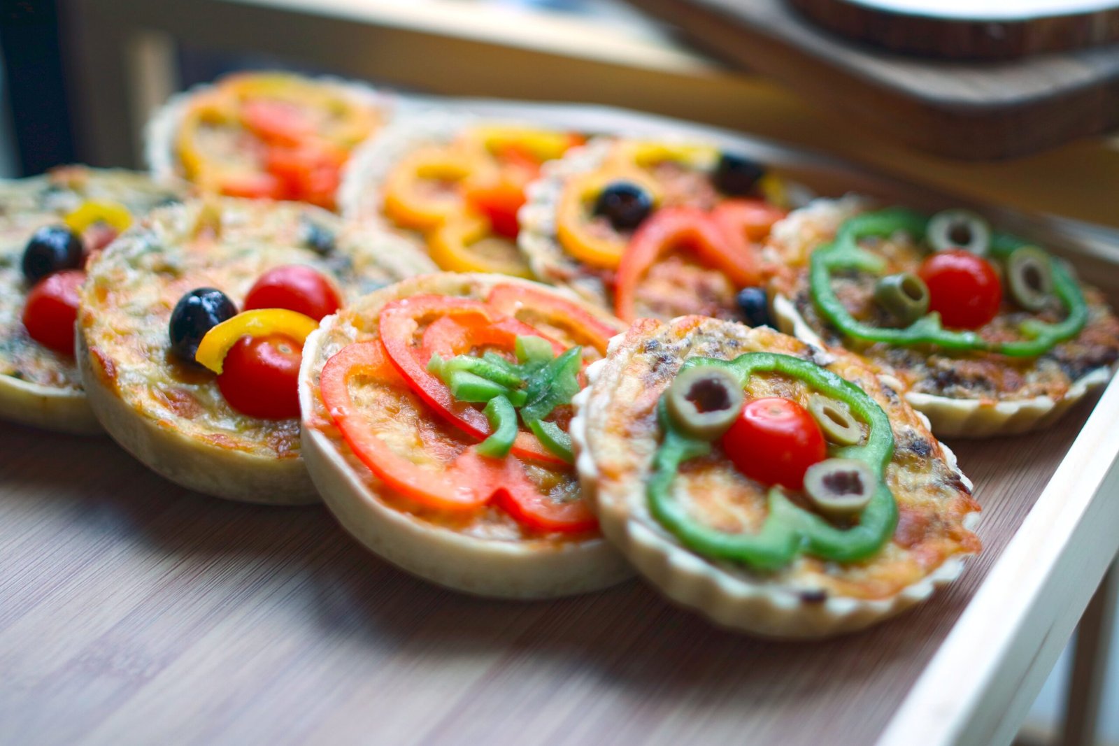 Small round veggie mini pizzas with peppers, cherry tomatoes, and olives
