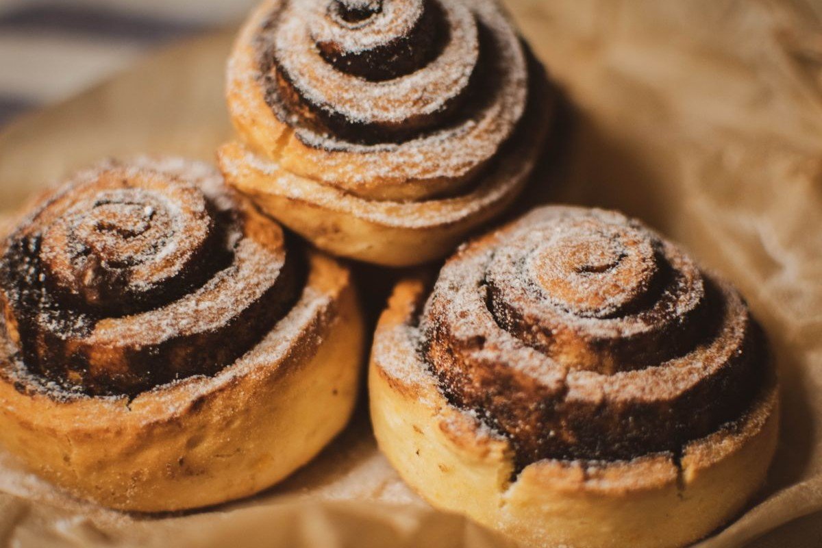 Soft & Fluffy Cinnamon Rolls (The 2-Hour Bakery-Style Recipe) 5 Three sugar-dusted cinnamon rolls on brown paper