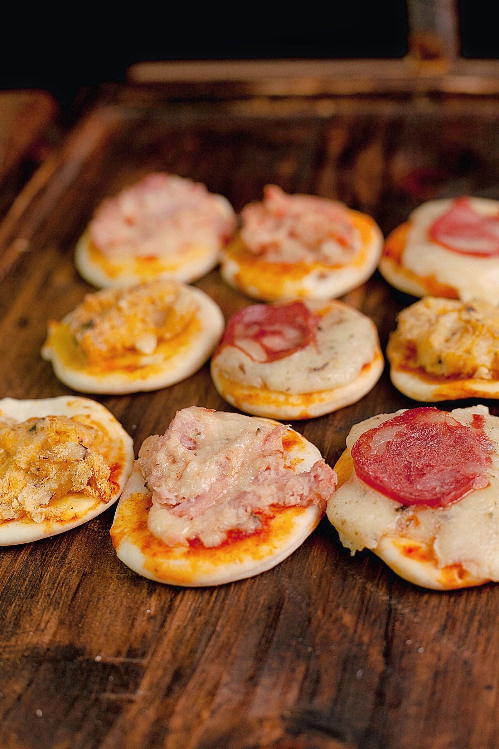 Mini pizzas with melted mozzarella on a rustic wooden table
