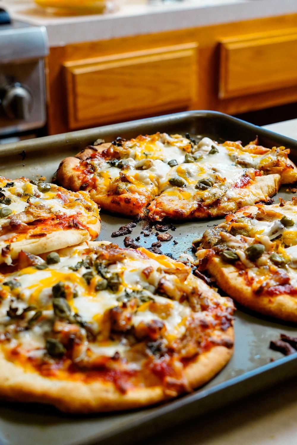 Personal-size pizzas with melted cheese on a sheet pan