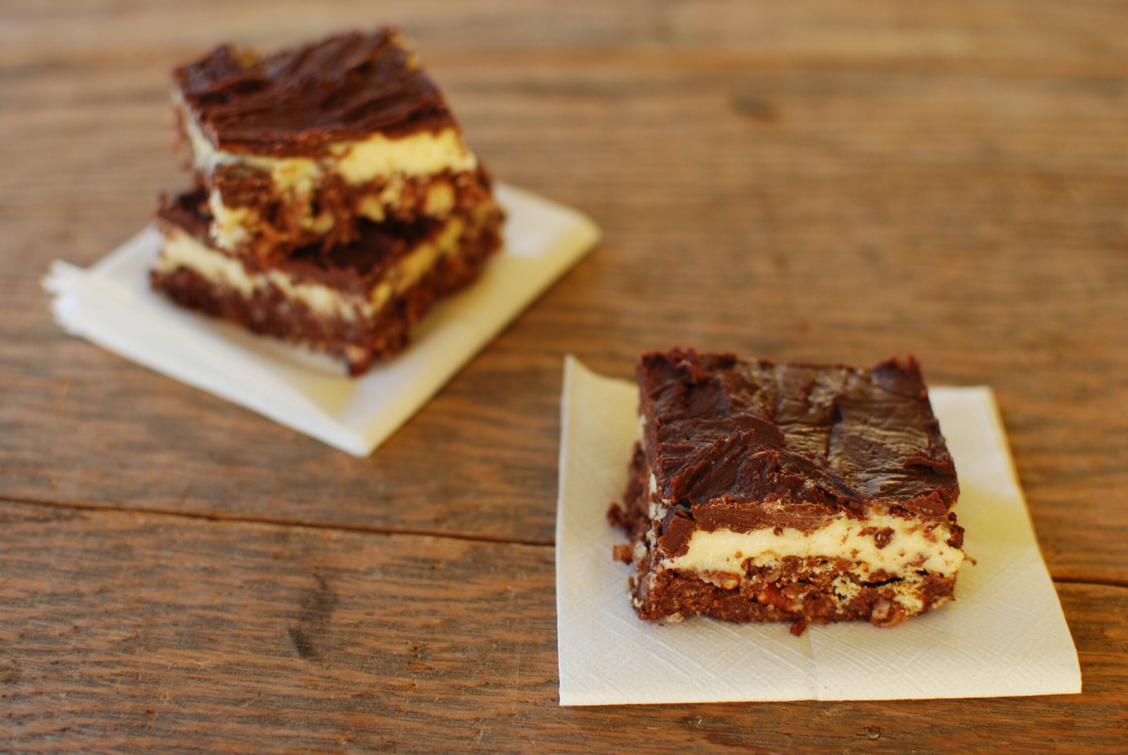 Stacked Nanaimo bars showing the chocolate crumb base, pale custard middle and glossy chocolate top