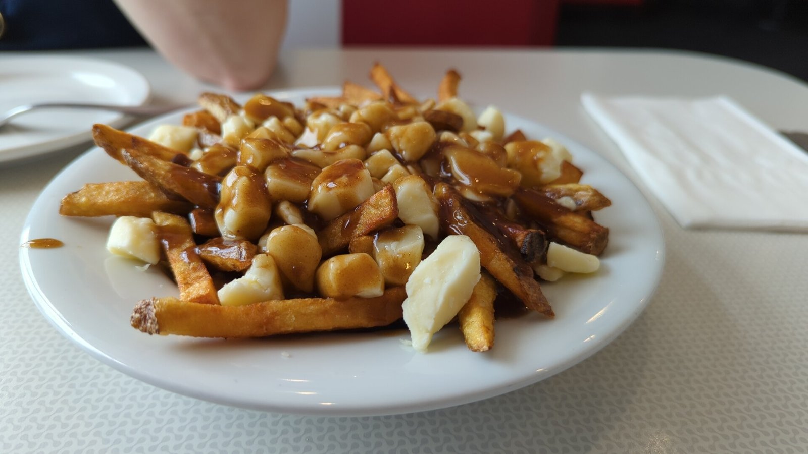 Classic poutine served on a plate: crispy fries, white cheese curds and brown gravy