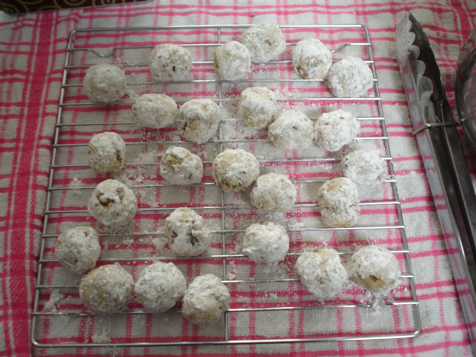 Russian Tea Cakes (Snowball Cookies, Buttery & Powdered-Sugar-Coated) 3 Powdered-sugar-coated tea cakes cooling on a rack