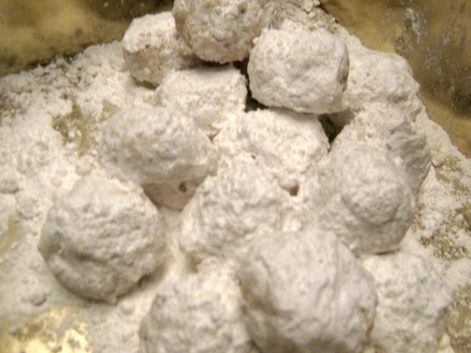 Russian Tea Cakes (Snowball Cookies, Buttery & Powdered-Sugar-Coated) 2 Round butter cookies thickly coated in powdered sugar, shown being rolled in a bowl of sugar