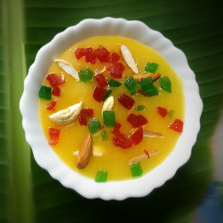 A bowl of creamy aamrakhand (mango shrikhand) topped with nuts.