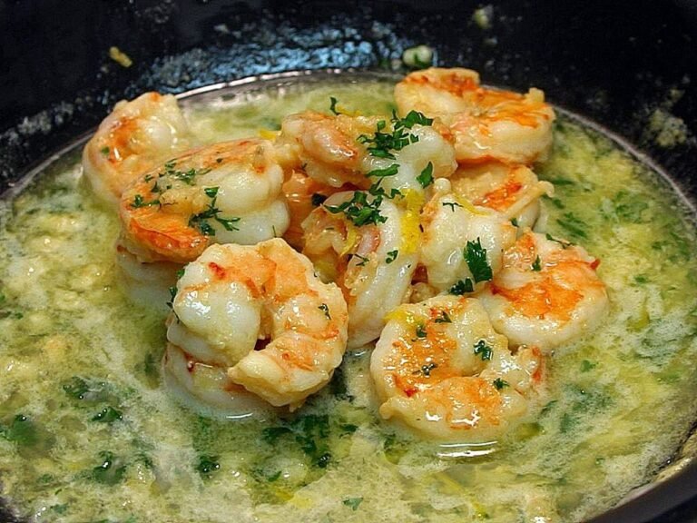 Shrimp scampi in a skillet, pink shrimp in glossy garlic butter sauce with fresh parsley and lemon zest