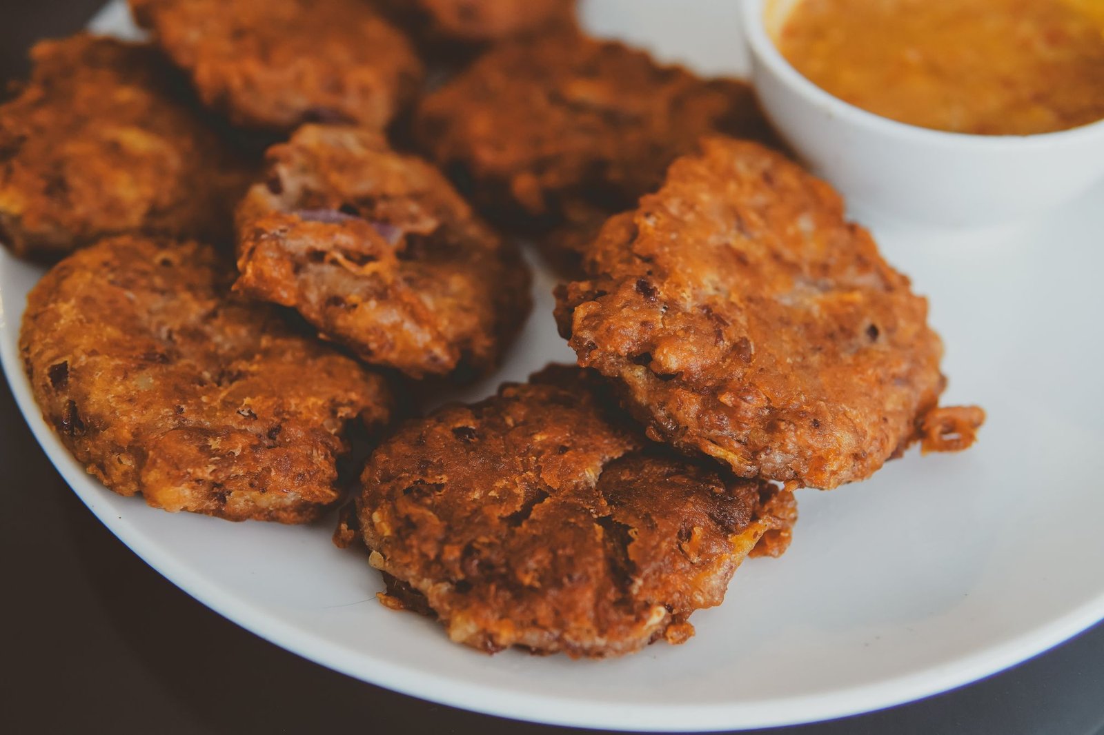Air Fryer Pumpkin Fritters (The Crispy 25-Minute Halloween Party Snack) 3 Air fryer pumpkin fritters on a plate with dipping sauce