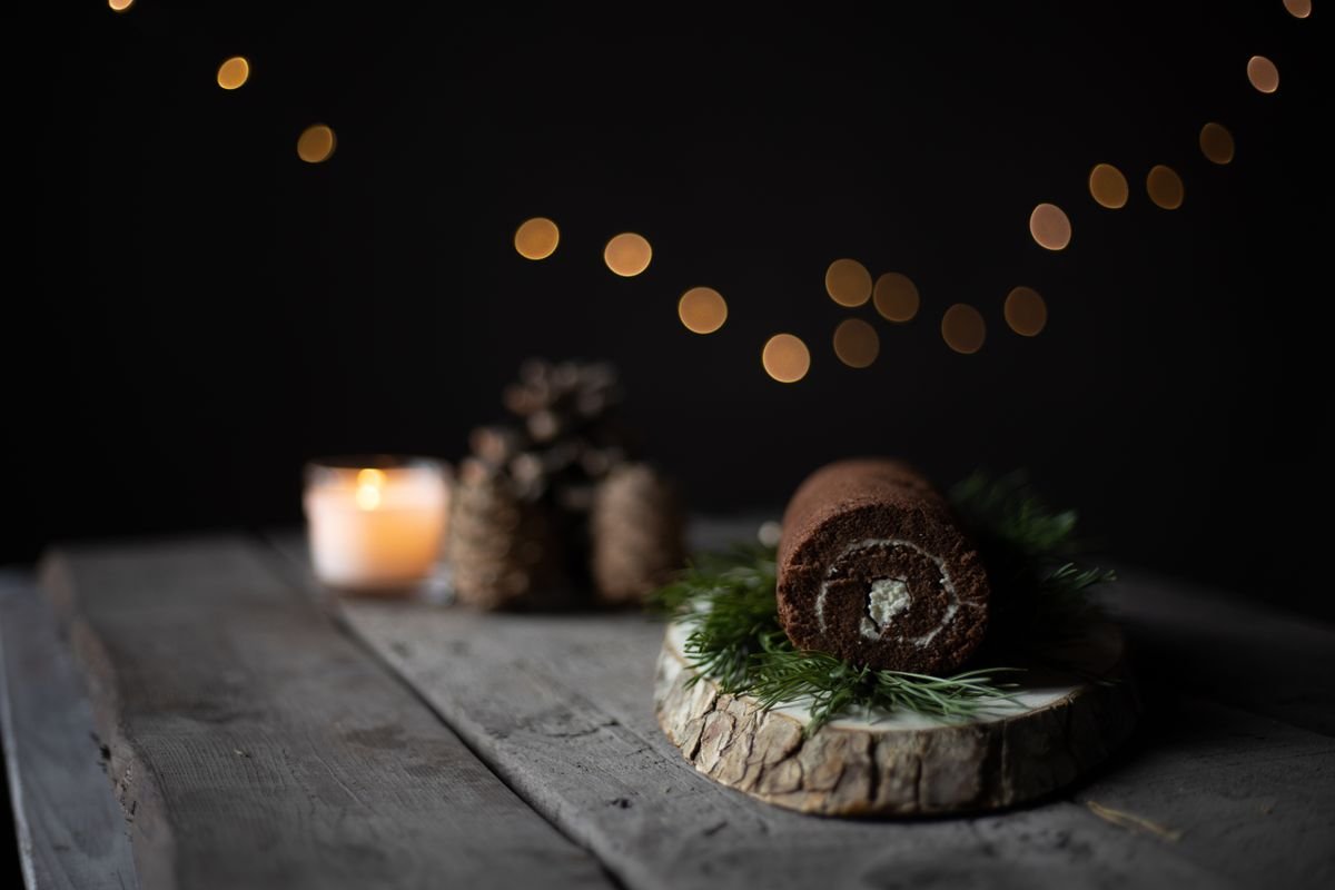 A whole chocolate cake roll with a cream spiral on a wooden board.